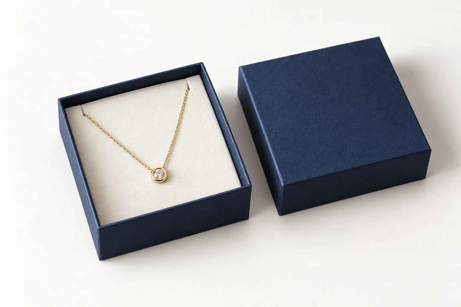 Compact navy lid-and-base jewelry box with a pendant necklace on an ivory insert