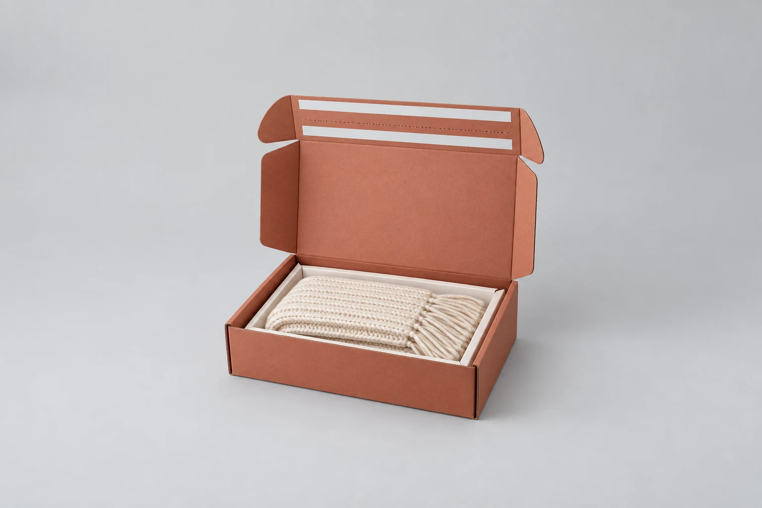 Terracotta mailer concept with two sealing liners and a paperboard cradle holding a knitted scarf